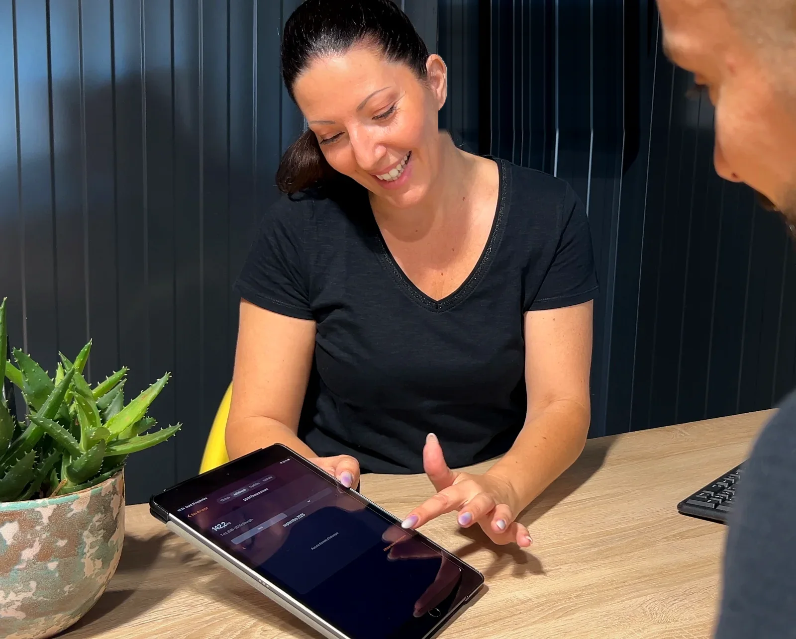 Une coach SLIMFIT sourit en montrant à une adhérente ses progrès sur une tablette